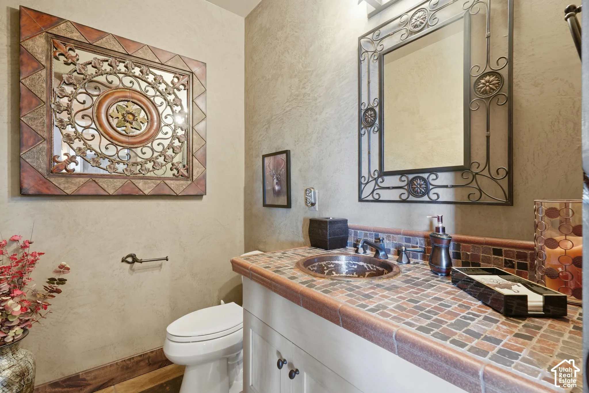 Vanity with a mosaic tile countertop, copper vessel sink, and an ornate metal-framed mirror