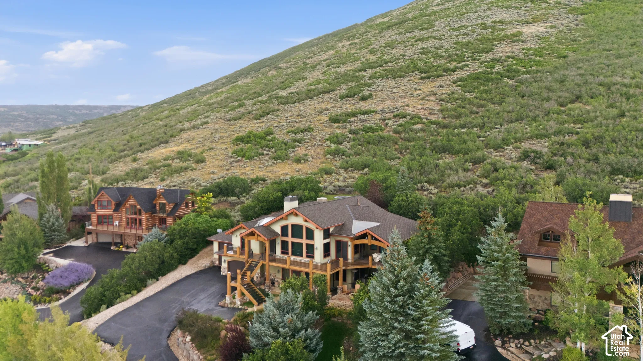 Multi-level property featuring extensive decking, prominent windows, and a multi-car driveway