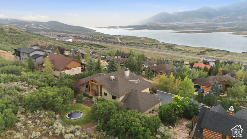 Spacious property featuring a large lawn, mature trees, and a distant lake with mountains