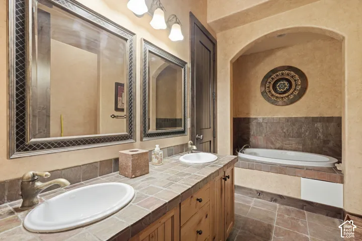 Dual vanity with tile countertop, individual mirrors, and wood-finish cabinetry