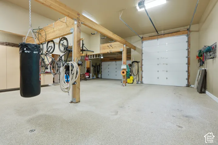 Spacious garage with multiple overhead doors, exposed wood beam construction, and built-in cabinetry