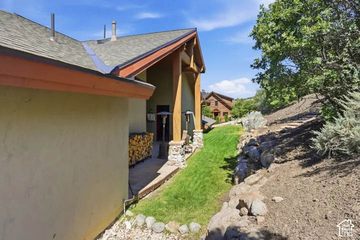 Stucco exterior with a pitched roof, rock-stacked columns, and a stone patio
