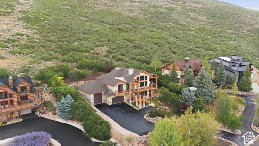 Multi-level residence with extensive landscaping, a two-car garage, and multiple decks