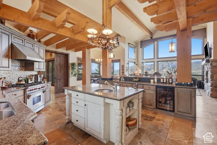 Gourmet kitchen with exposed wood beams, granite countertops, tile backsplash, stainless steel appliances, and a built-in wine refrigerator