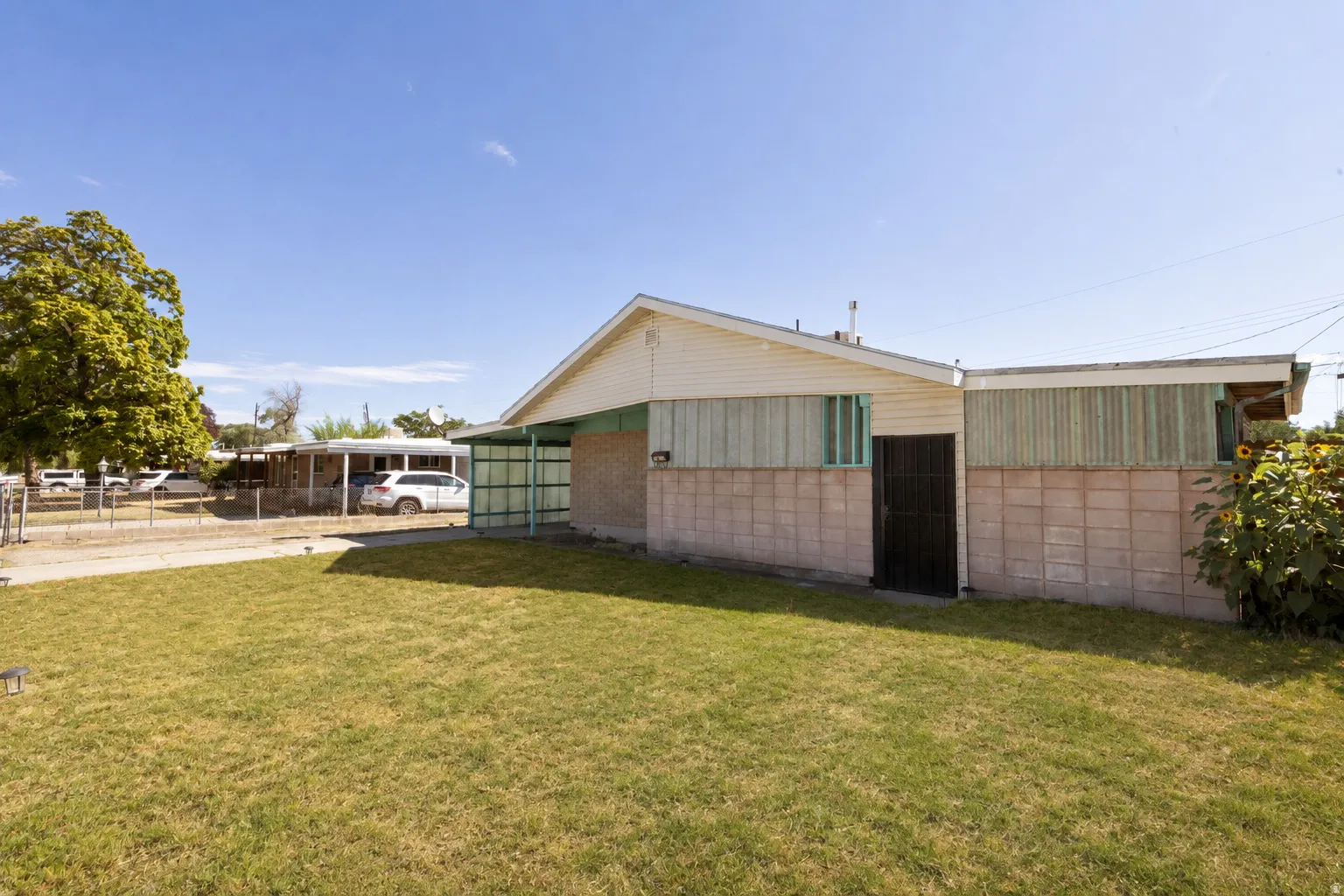 Expansive lawn area, concrete block exterior, secured entry door, and perimeter fencing