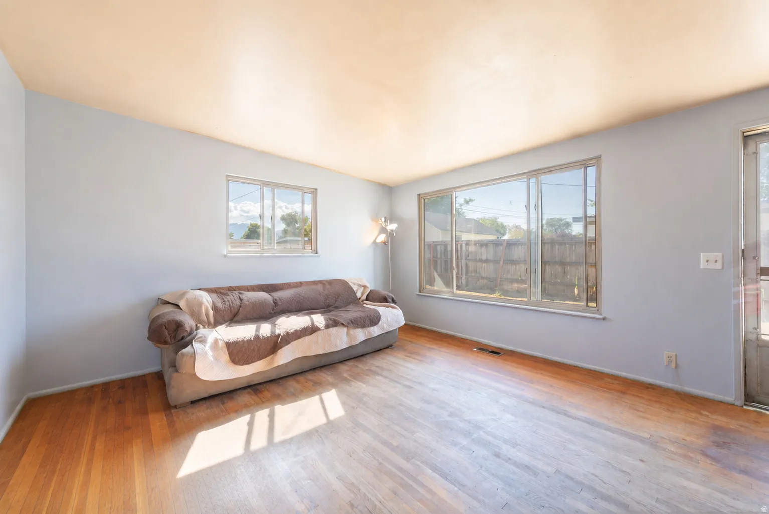 Hardwood flooring, light blue wall paint, and multiple windows