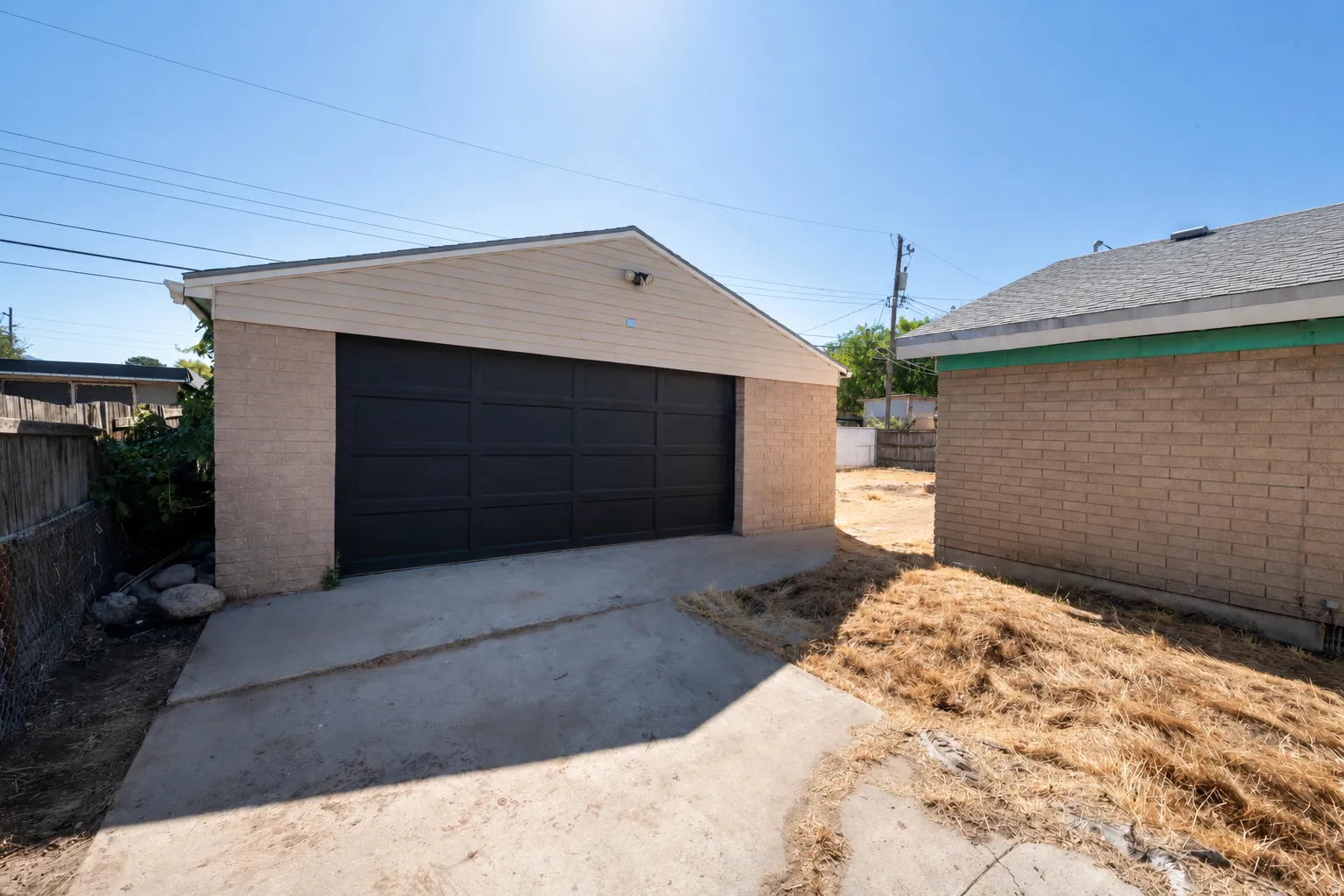 Detached garage with a dark panel door, siding, and concrete driveway