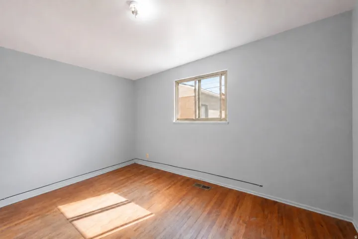 Hardwood flooring, light gray wall finish, window with natural light, and ceiling-mounted light fixture