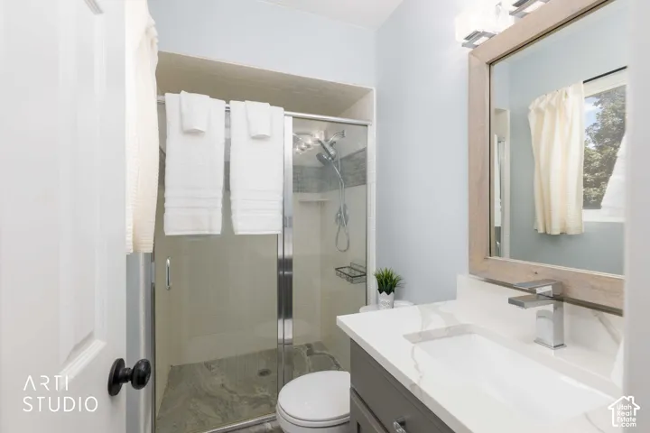 Primary bathroom. Glass-enclosed shower with a tiled surround, single vanity with a white countertop, chrome faucet, and a large framed mirror.