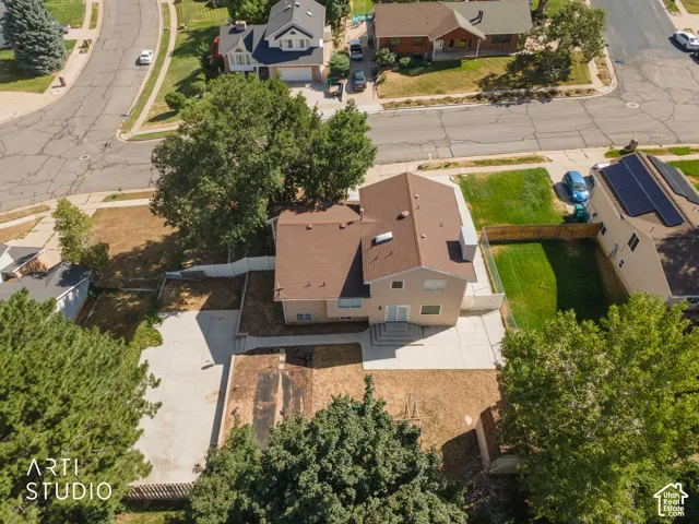 Rear exterior featuring a concrete patio, mature trees, and a residential neighborhood setting