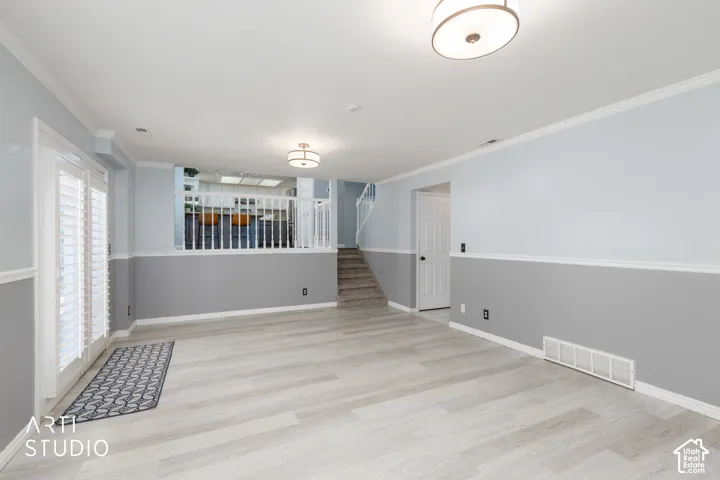 Light wood-finish flooring, two-tone wall treatment, white trim, recessed lighting, and a white interior door