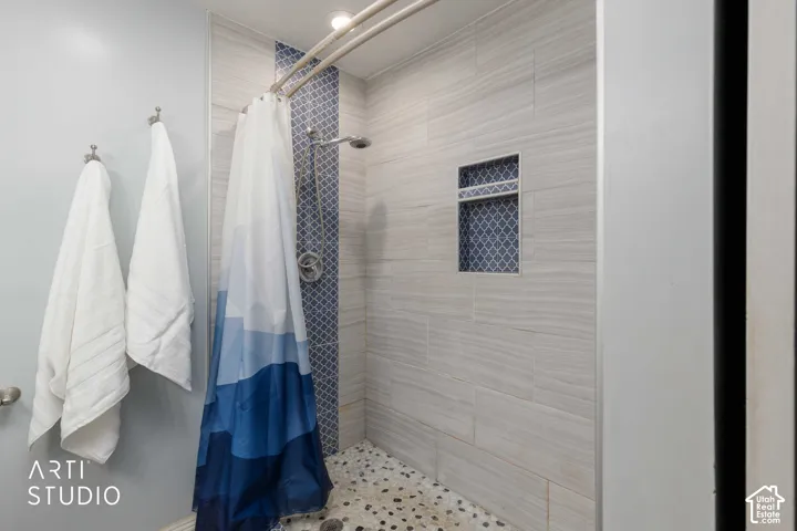 Shower enclosure featuring a tiled accent stripe, built-in recessed shelf, and pebble flooring