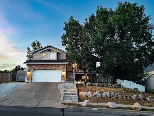 Brick and siding exterior with an attached two-car garage, mature landscaping, and a multi-level concrete driveway