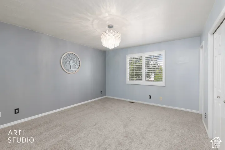 Primary bedroom with white plantation shutters, light gray wall finish, and a ceiling-mounted decorative light fixture