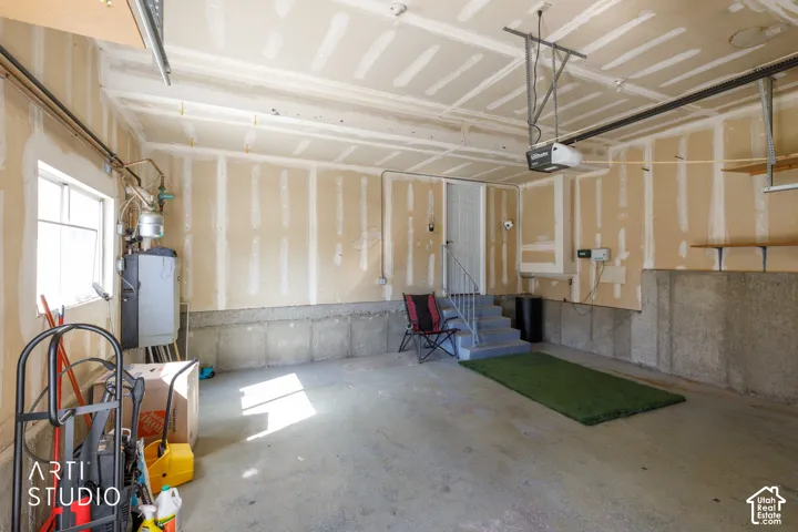 Spacious garage with concrete flooring, utility window, built-in shelving, and direct interior access