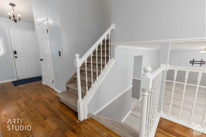 Wood-finish flooring, staircase with carpeting and white balusters, and a white paneled door