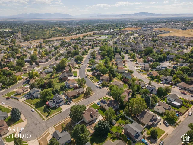 Residential neighborhood with established homes, mature trees, paved streets, and distant mountains