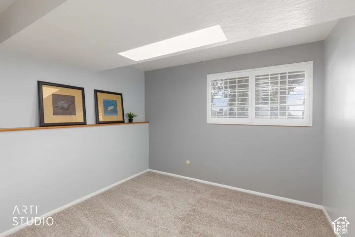 Recessed ceiling light panel, window with white plantation shutters, light grey wall paint, and neutral tone carpet