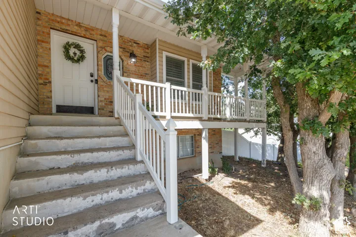 Brick and siding exterior featuring a covered porch, white railing, white entry door, and exterior lighting fixture