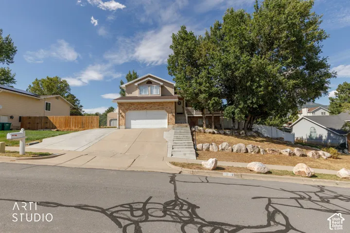 Property exterior featuring a concrete driveway, attached garage, and mature trees