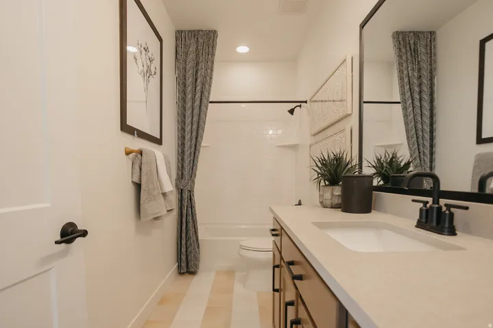 Bathroom featuring a single vanity with an integrated sink, dark wood-finish cabinetry, and a black-framed mirror