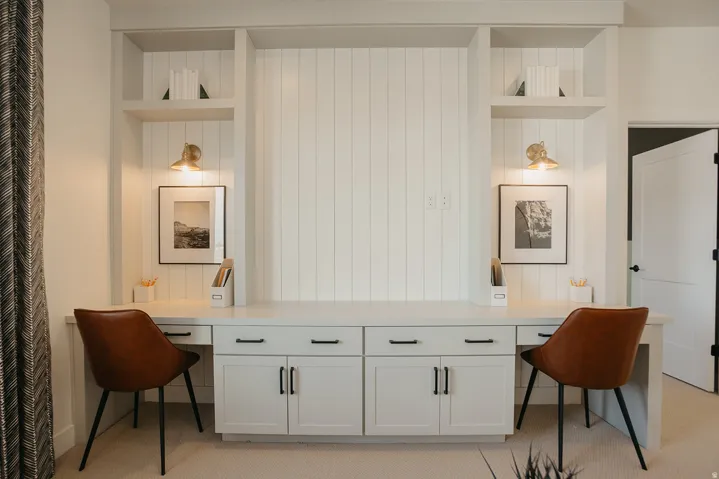 Built-in desk with dual workstations, integrated shelving, vertical shiplap detailing, and brass wall sconces