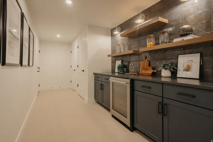 Built-in cabinetry with dark countertops, a beverage refrigerator, and open shelving against a tiled accent wall