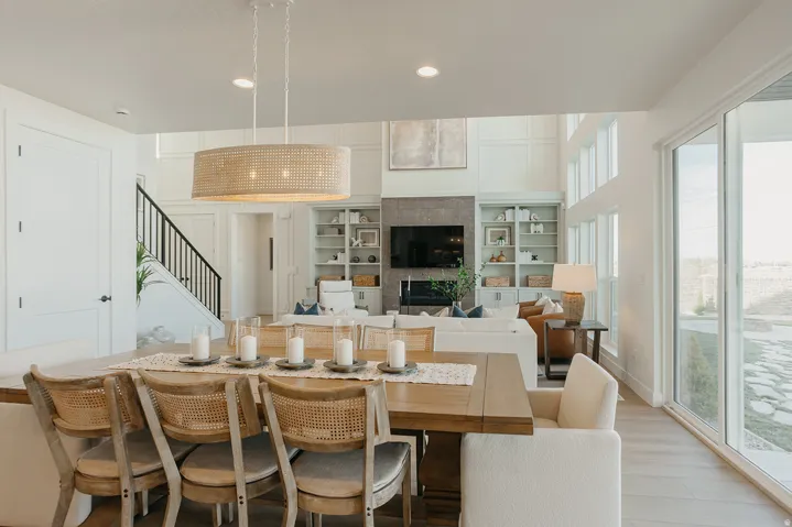 Open-concept living area with a double-height ceiling, large sliding glass doors, built-in shelving, and a prominent fireplace feature
