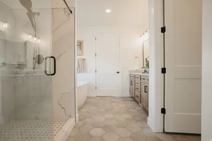 Walk-in shower with clear glass enclosure and marble-look tile surround