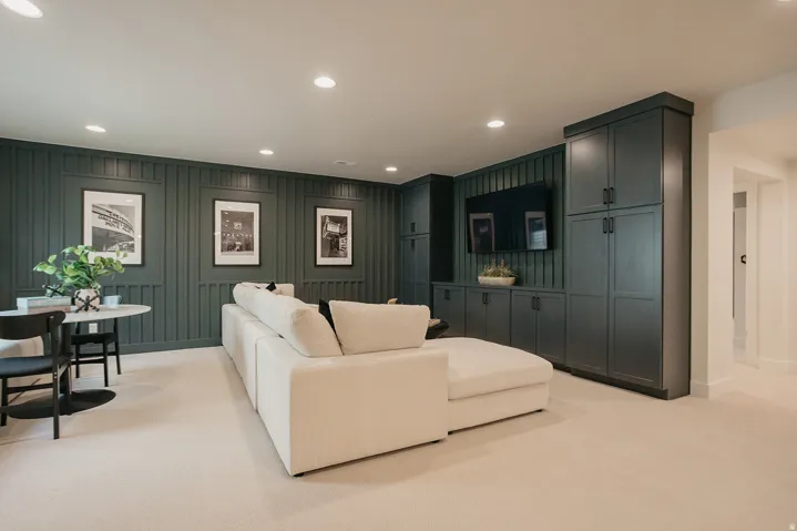 Recessed lighting, built-in cabinetry, vertical paneling detail, wall-mounted television, and light-toned carpeting