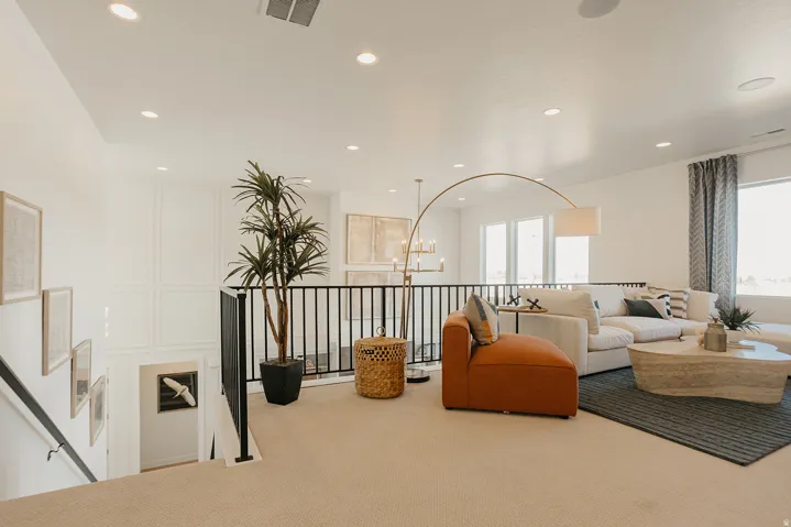 Carpeted loft area with recessed lighting, black metal railing, and white paneled accent wall