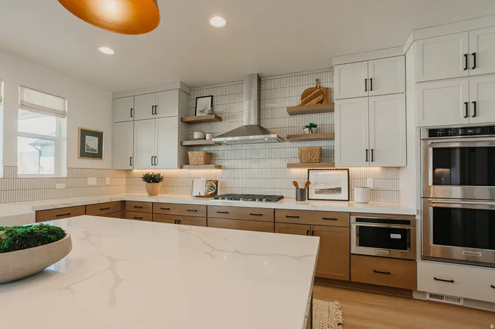 White quartz countertops, dual-toned cabinetry, stainless steel appliances, and a full-height tiled backsplash