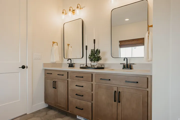 Dual vanity with light wood-finish cabinetry, matte black hardware, and integrated sinks