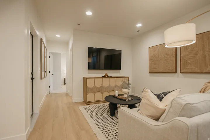 Recessed lighting, light wood-finish flooring, white walls, and a mounted television
