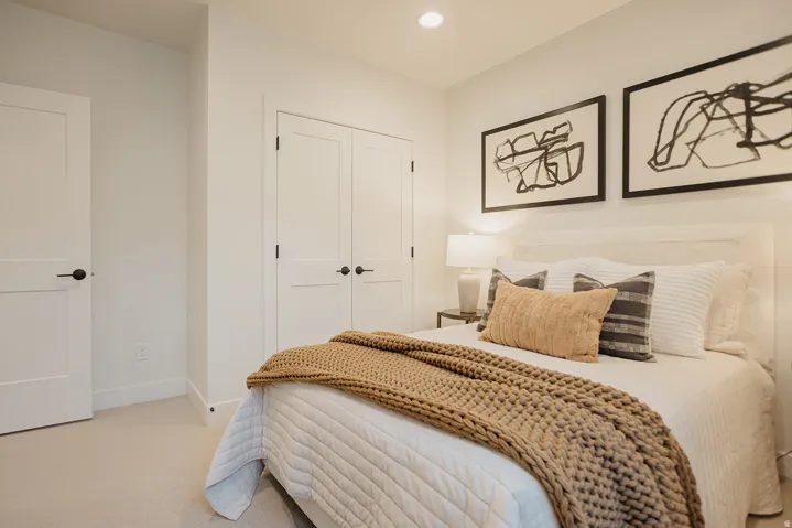 Recessed ceiling lighting, white walls, two-panel solid core doors with matte black hardware, and neutral-toned carpeting