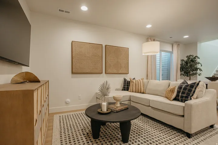 Recessed lighting illuminates the living area with light wood-finish flooring