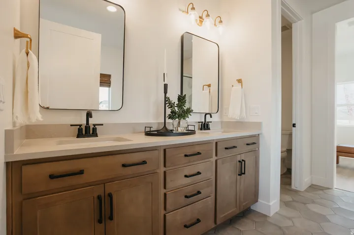 Dual wood-finish vanities with light-toned countertops, matte black hardware, and rectangular mirrors