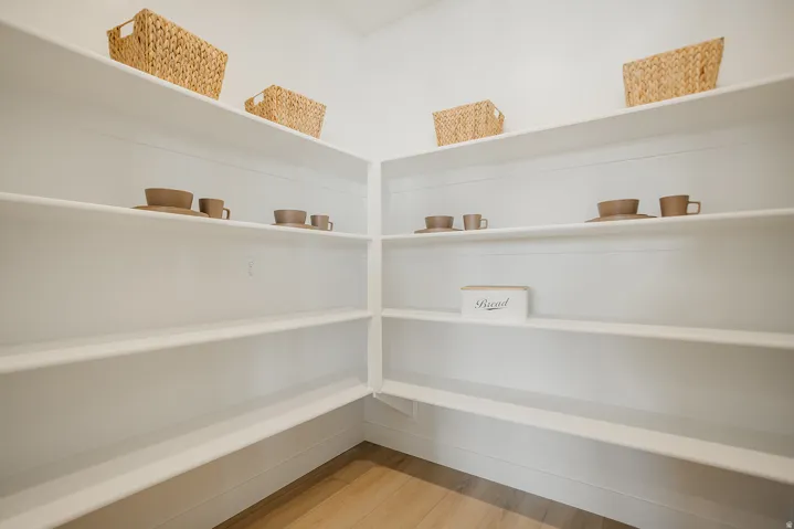Built-in shelving with L-shaped configuration, white finish, and wood-finish flooring