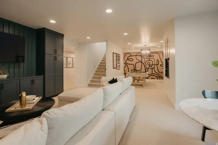 Built-in entertainment cabinetry with dark paneling, recessed lighting, carpeted flooring, a visible staircase, and a chandelier
