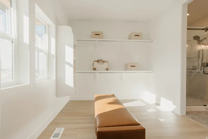 Built-in closet shelving, multiple windows, built-in wall cabinet, wood-finish flooring, glass-enclosed shower
