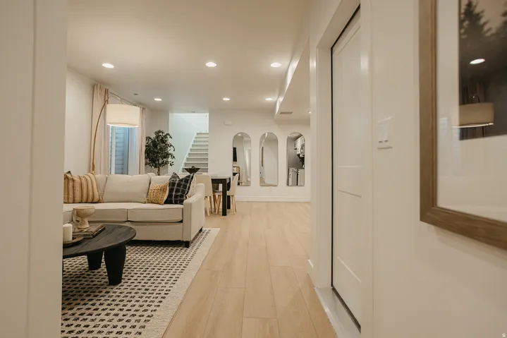 Recessed ceiling lighting, light wood-finish flooring, white paneled interior doors, and a staircase with white risers