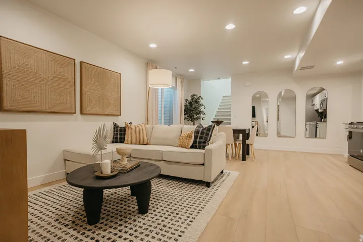 Open-concept living area with light wood-finish flooring, recessed lighting, and a contemporary staircase