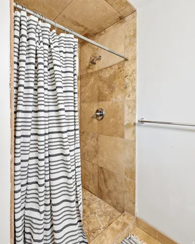 Tiled shower enclosure featuring a chrome shower head and control