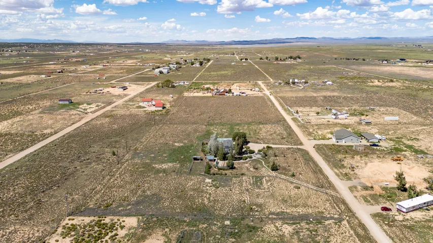 Expansive land parcel featuring existing residential structures, established roads, and distant mountain topography