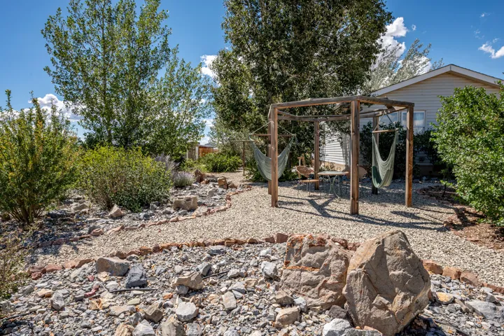 Gravel pathways with stone edging, mature landscaping, and a wooden pergola structure