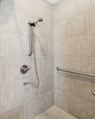 Shower enclosure featuring large format wall tiling and a handheld shower head