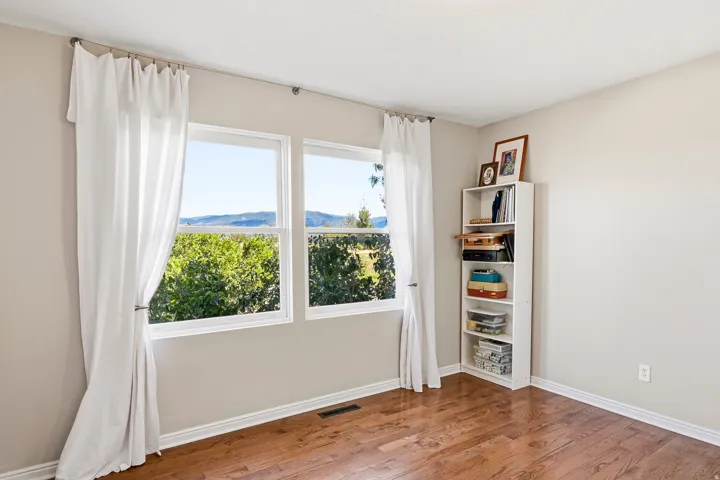 Wood-finish flooring, light neutral wall color, built-in shelving, and two windows
