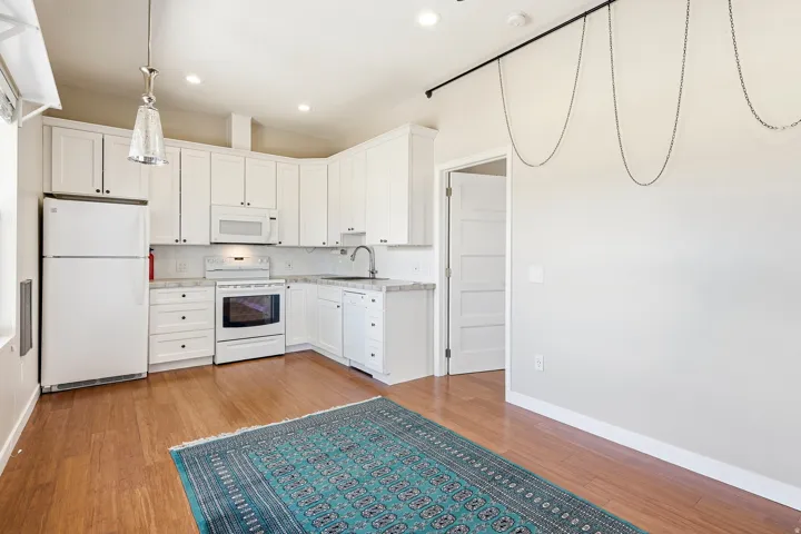 Kitchen featuring white cabinetry, white appliances, recessed lighting, and wood-finish flooring