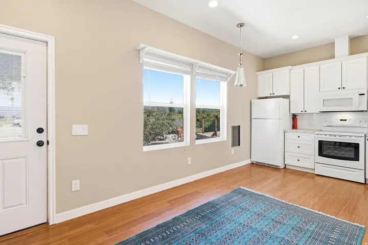 Kitchen featuring white cabinetry, white appliances, wood-finish flooring, recessed lighting, and a pendant light fixture