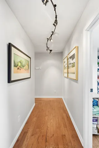 Hardwood flooring, track lighting, and a white interior door
